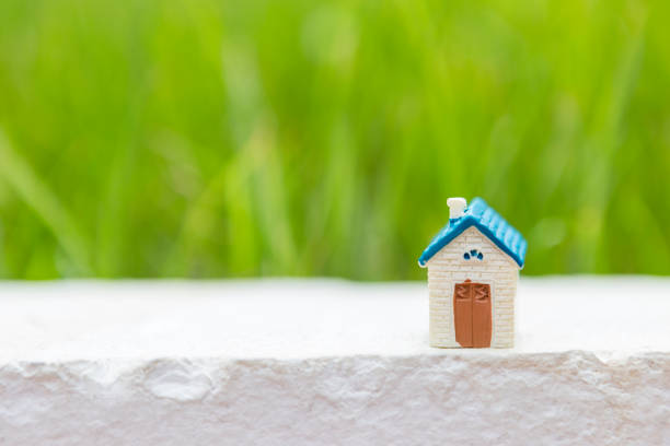 Miniature house over blurred green garden background, house load or property business, outdoor day light