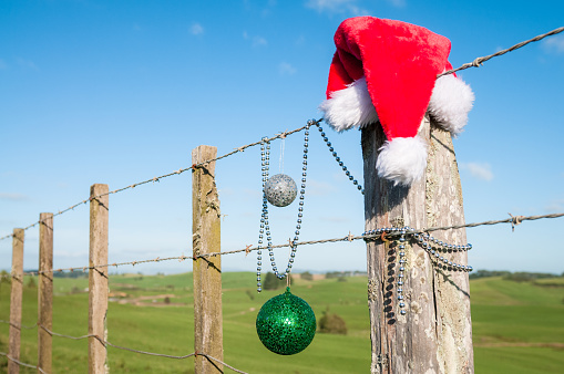 A santa hat and other Christmas decorations on a fence in the southern hemisphere during December.