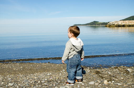 Baby boy in shore of St. Lawrence river during summer day in Gaspesie (Les Mechins)