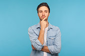 Hmm, let's think! Portrait of pensive handsome man in worker denim shirt touching chin while pondering plan