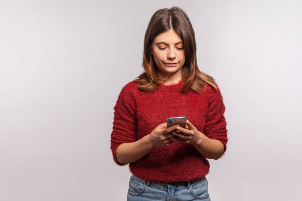 istock Brunette woman in shaggy sweater using mobile phone with attentive serious expression, typing or reading message on social network 1269872484