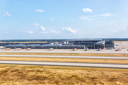 LONDON, UK - JUNE 12, 2018: Aerial view of planes from Saudia and Emirates Airline parked at Terminal 4 of London's Heathrow Airport on a sunny summer morning.  The Crown Plaza hotel is just beyond the terminal.