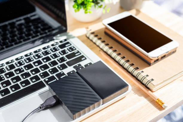 istock External Hard Disk on Laptop Keyboard with smartphone on notebook,a pencil and flower pot tree on wooden background,Top view office table. 1269881263