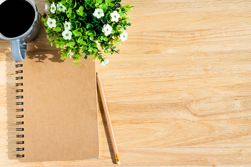 notebook,flower pot tree,a pencil and coffee cup on wooden background,Top view with copy space office table.