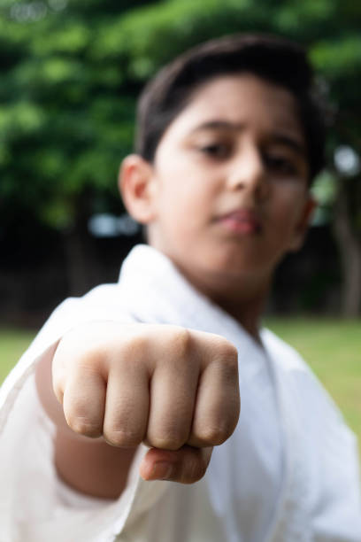 istock Kid Boy With Focus On Punch And Blur Face Pose For Martial Arts Practice Wearing White Karategi Kimono 1269882025