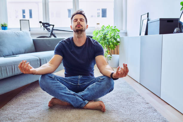 istock Handsome man meditating at home sitting on the floor 1269882452