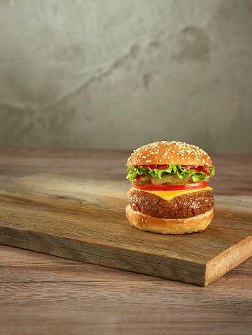 Delicious cheeseburger on cutting board.