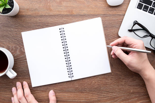 istock Man hand is going to write something on blank notebook pages. Top view, flat lay. 1269882617