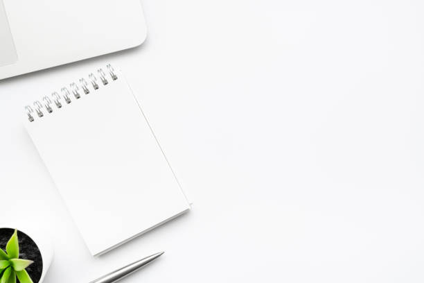 istock White office desk table with blank notebook with pen and laptop computer. Top view with copy space, flat lay. 1269882629