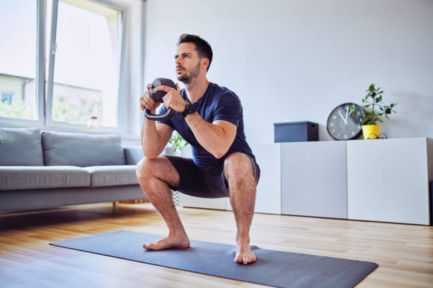 istock Training at home, young man doing squats with kettlebell weights. 1269883298