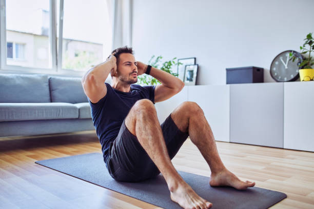 hombre deportivo haciendo ejercicio de sentadas durante el entrenamiento en casa - músculo abdominal fotografías e imágenes de stock