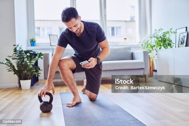 Man With Smartphone Checking Training App Before Home Workout Exercises Stock Photo - Download Image Now