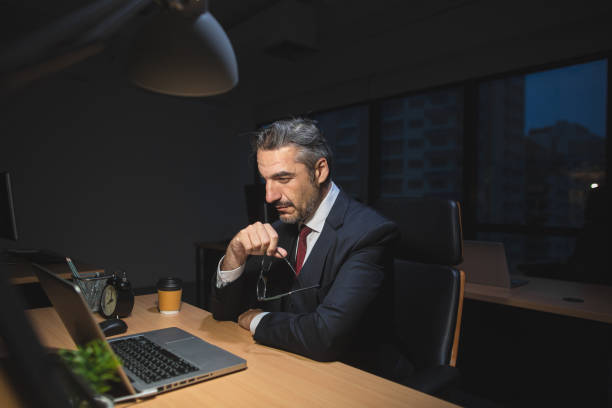 istock Senior business man working overtime late night using laptop at office 1269884485