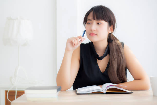 istock Beautiful asian woman writer smiling thinking idea and writing on notebook or diary with happy on desk office, lifestyle of asia girl is success, female planning working, education and business concept. 1269896998