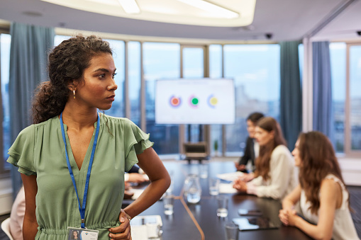 Attractive woman working by conference table. Team in background