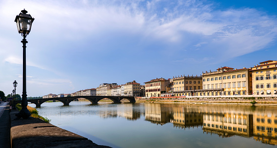 A warm late afternoon light illuminates the Arno riverbank in Florence