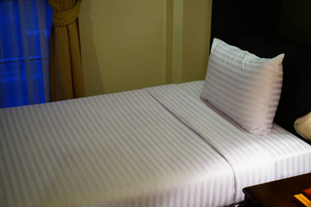 istock Bed with clean white pillows and bed sheets in beauty room 1269913202