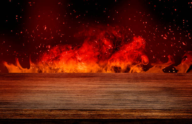 istock Empty wooden table top with orange fire or flame and sparkles in dark room. 1269914297