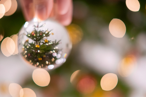 Close up of a crystal ball with reflection of a christmas tree. Defocused light on the background.