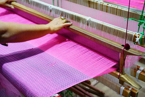 Woman hand weaving silk in traditional way with manual Loom
