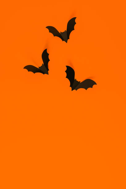 istock Cartoon halloween background black bats on orange backdrop. Bright holiday backdrop for your design. Dark and moody background. 1269916087