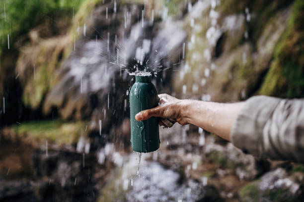 l'uomo riempie la sua bottiglia di acciaio inossidabile con acqua pulita e fresca - water bottle water bottle drinking foto e immagini stock