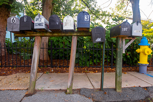 Chesapeake City, MD, USA 08/26/2020: A close up wide angle image of a group of vintage galvanized metal mail boxes on wooden posts. They all have house numbers on them, some alseo show the owner.