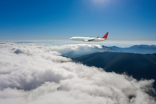 Passenger jet airplane flying above clouds.