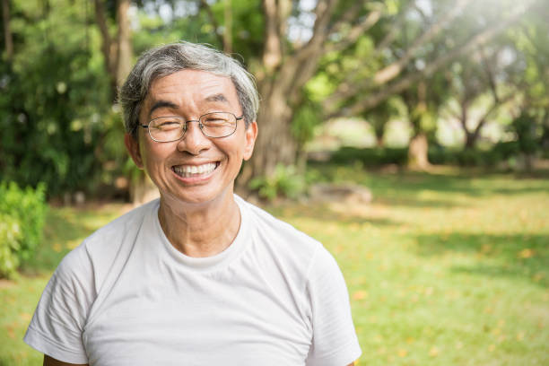 verticale du vieil homme asiatique aîné heureux en bonne santé dans le parc à l’extérieur avec l’espace de copie. concept de retraite de style de vie de soins de santé de printemps - oncle photos et images de collection