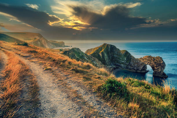 Dramatic Sky Over English Landscape Durdle Door Famous  Beach in England Dramatic Sky Over English Landscape Durdle Door Beach in England. Outdoor Path true English Cliffs near Durdle Door Favorite English Beach. durdle door stock pictures, royalty-free photos & images