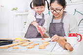 小さなアジアの女の子と彼女の母親が台所でケーキとクッキーを焼く肖像画。幸せなアジアの家族と母の日の概念
