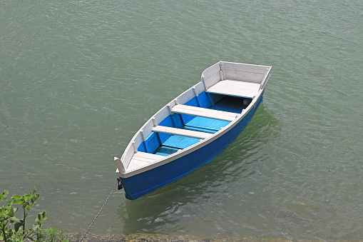 blue wooden boat is chained to the dock