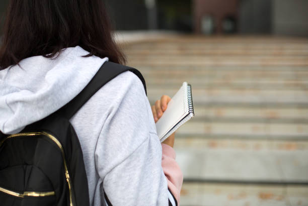 istock A female student with a black backpack and a notebook in her hands stands on the steps in front of the Institute. Higher education, the beginning of the school year, back to school. Copyspace 1269938706