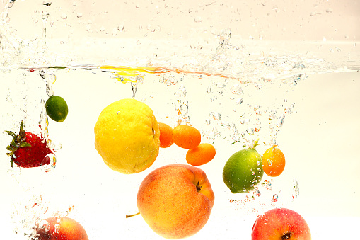 Lemon apple strawberry kumquat lime peach falling in water