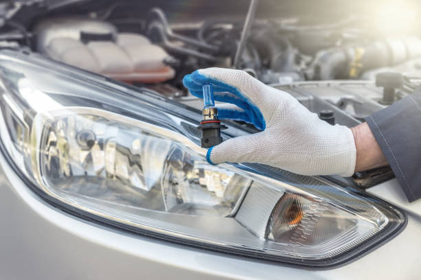 istock Repairment holding new car light bulb under deception for headlamp, car as background 1269940811