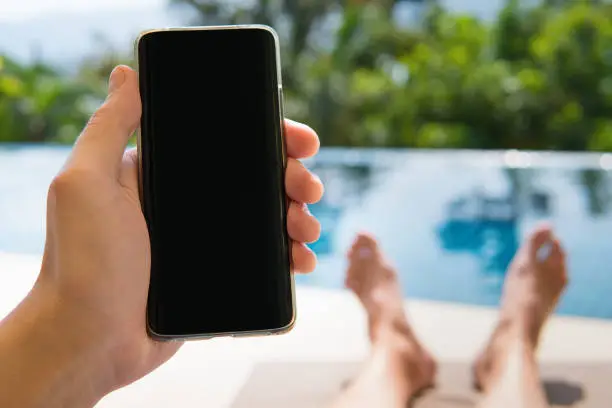 Photo of Smartphone in hand closeup on pool background