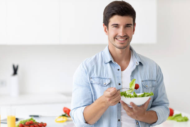 istock Smiling man holding plate with fresh vegetables on modern kitchen at home. 1269949278