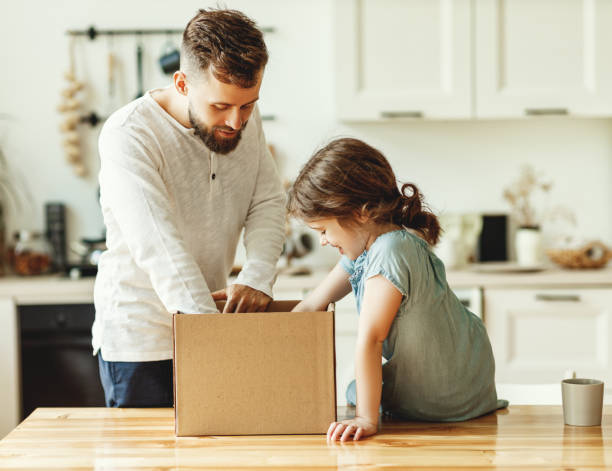 Father and kid unpacking carton box at home