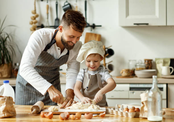 istock Father and little boy kneading dough together 1269949596