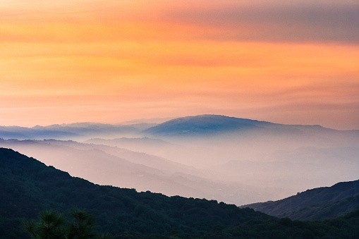 Sunset views in Santa Cruz mountains; Smoke from the nearby burning wildfires, visible in the air and covering the mountain ridges and valleys; South San Francisco Bay Area, California