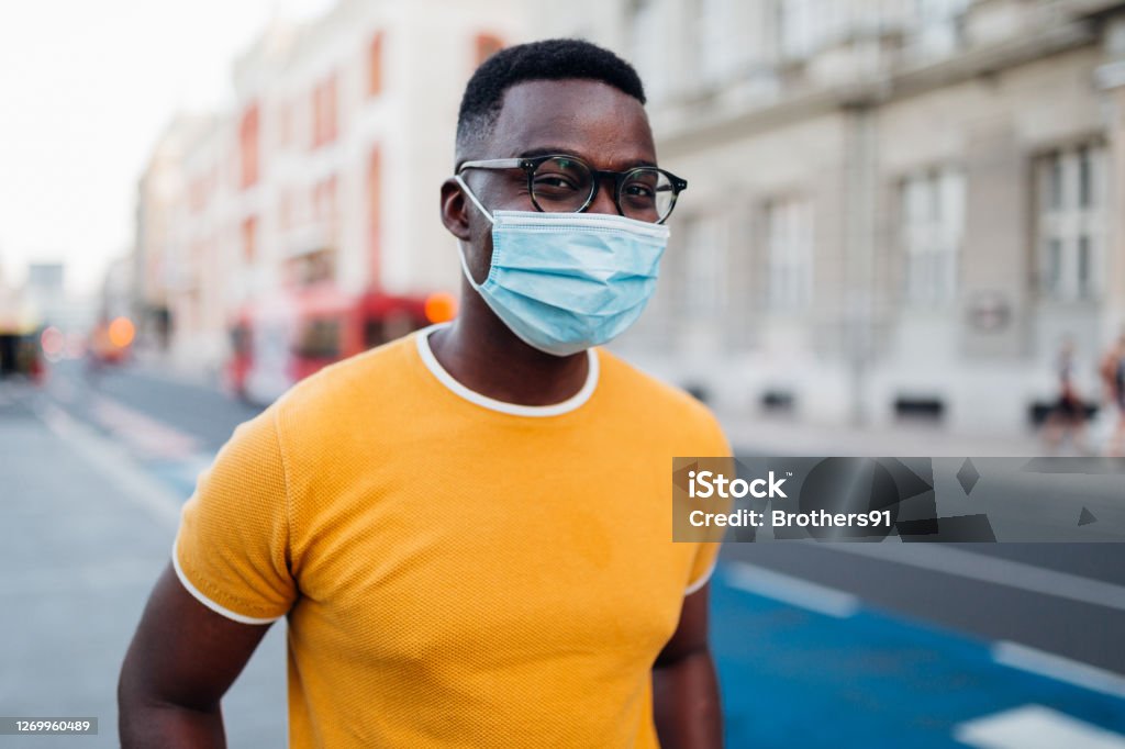 Portrait of a young African American man wearing a face mask Concept, safety, protection, virus, pandemic, corona virus, flu, germs, responsibility, new age. Portrait of a young handsome African American man wearing and smiling behind his protective face mask Men Stock Photo