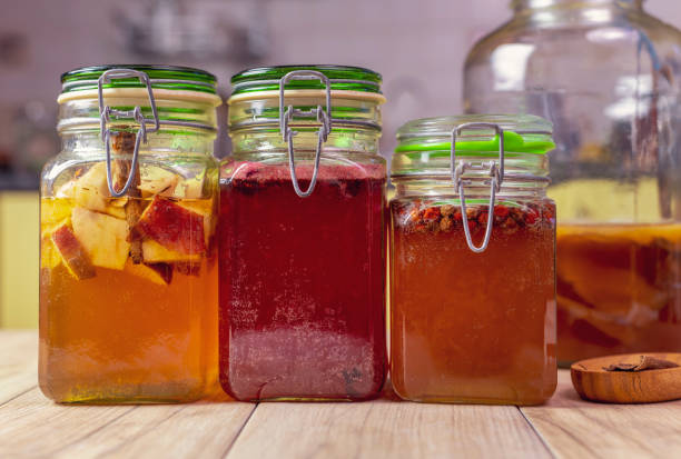 istock Second fermentation of kombucha tea. Making healthy drinks at kitchen. Left to right, apples and cinnamon, hibiscus and rose leaves, red juniper berries and jar with a kombucha scoby. 1269963443