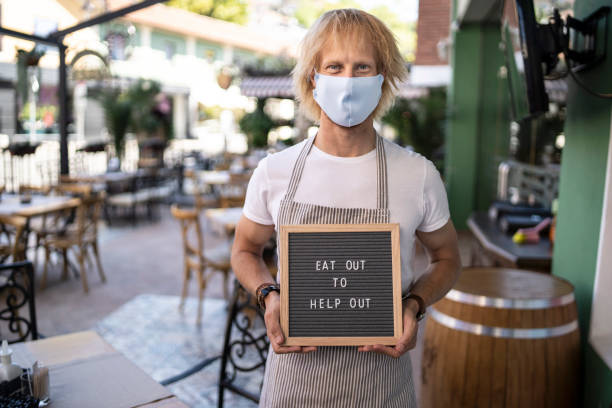 istock Man holding sign Eat out to help out 1269965973