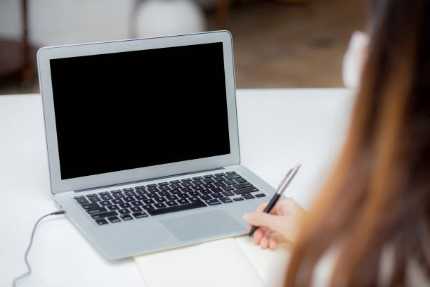 istock Young asian woman writing on notebook for planning working and using laptop computer blank screen on desk at home, girl notes, female study and learning, business and communication concept. 1269972847