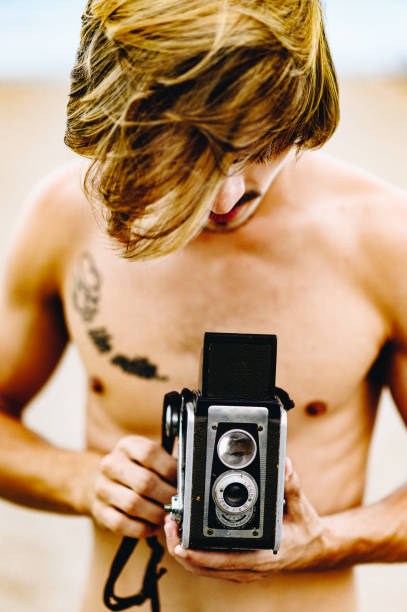 istock Handsome guy with vintage camera on the beach 1269980781