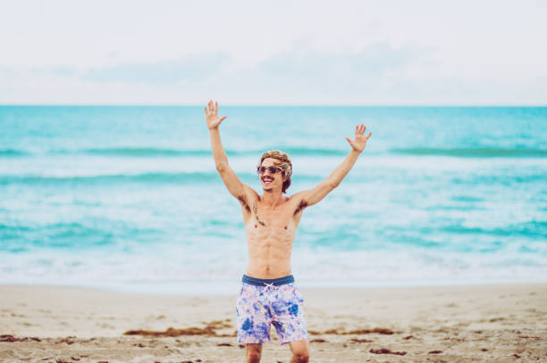 istock Excited young guy raises his hands up at the beach 1269984658