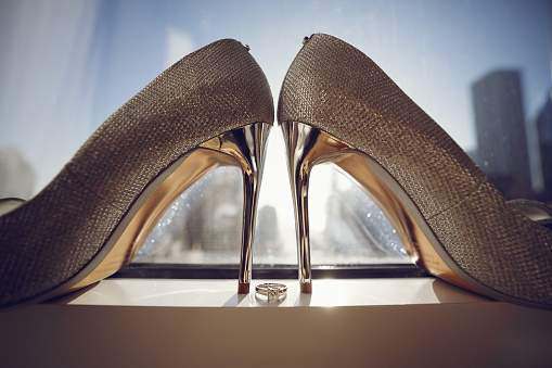 Bride's silver shoes. Elegant wedding shoes with ring in a windowsill