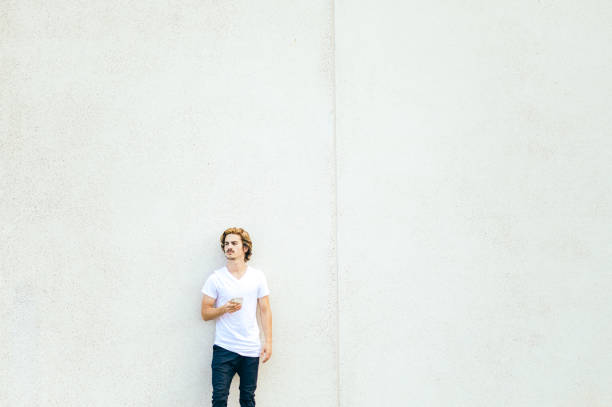 istock Handsome young man uses cell phone, minimalistic urban background 1269986782