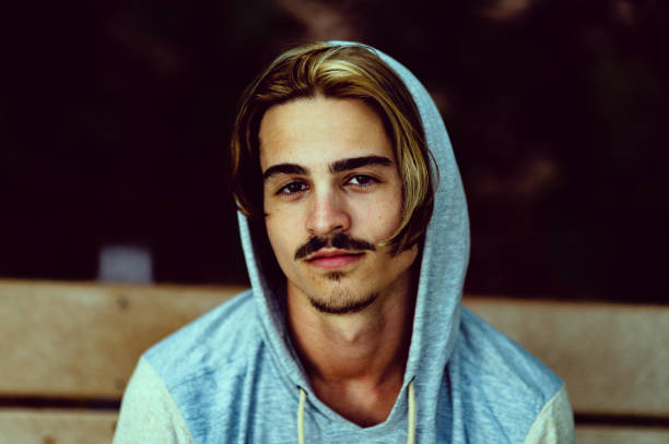 Handsome young millennial age guy wearing a hoodie sweatshirt in a moody portrait