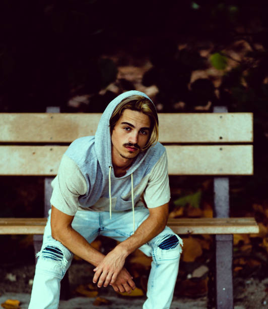istock Rebellious guy in a hooded shirt on a park bench 1269987150